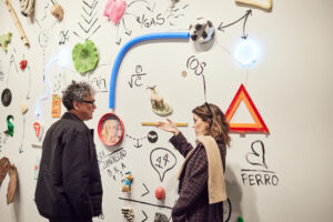 two people looking at art installation of wall drawings and found objects