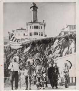 Native Americans in feather headgear land on Alcatraz Island as protest.